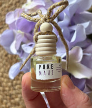 Load image into Gallery viewer, Car diffuser in a small apothecary bottle in the Pure Maui scent held in a hand in front of a green leafy background.
