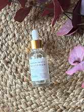 Load image into Gallery viewer, Bottle of Sandalwood &amp; Saffron scented oil with dropper on a textured surface with a plant in the background.
