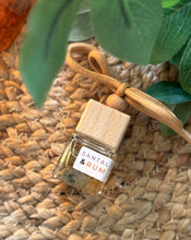 Load image into Gallery viewer, A Bungalow Candle Studio car diffuser in the Santal &amp; Rum scent displayed with foliage
