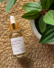 Load image into Gallery viewer, Bottle of Santal &amp; Rum scented oil with a dropper on a woven surface with a plant in the background
