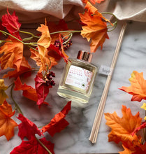 Load image into Gallery viewer, A flay lay of Spokane Sweater Weather reed diffuser with wooden reads and fall leaves next to it.
