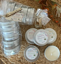 Load image into Gallery viewer, Travel Tin Candles in two bundles and stacked individually with labels indicating various fall scents, arranged on a woven surface with decorative pumpkins and leaves in the background.
