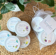 Load image into Gallery viewer, Collection of white tin travel candles with labels of spring scents on a woven surface, featuring 'Bungalow Studio' branding.
