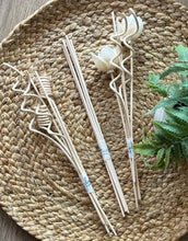 Load image into Gallery viewer, Three bundles of natural wood reed in different shapes arranged on a round woven straw mat with a green plant sprig in the corner.
