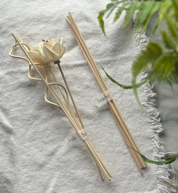 Two bunches of Floral and spiral-shaped wood reeds and straight wood reeds lying together on table.