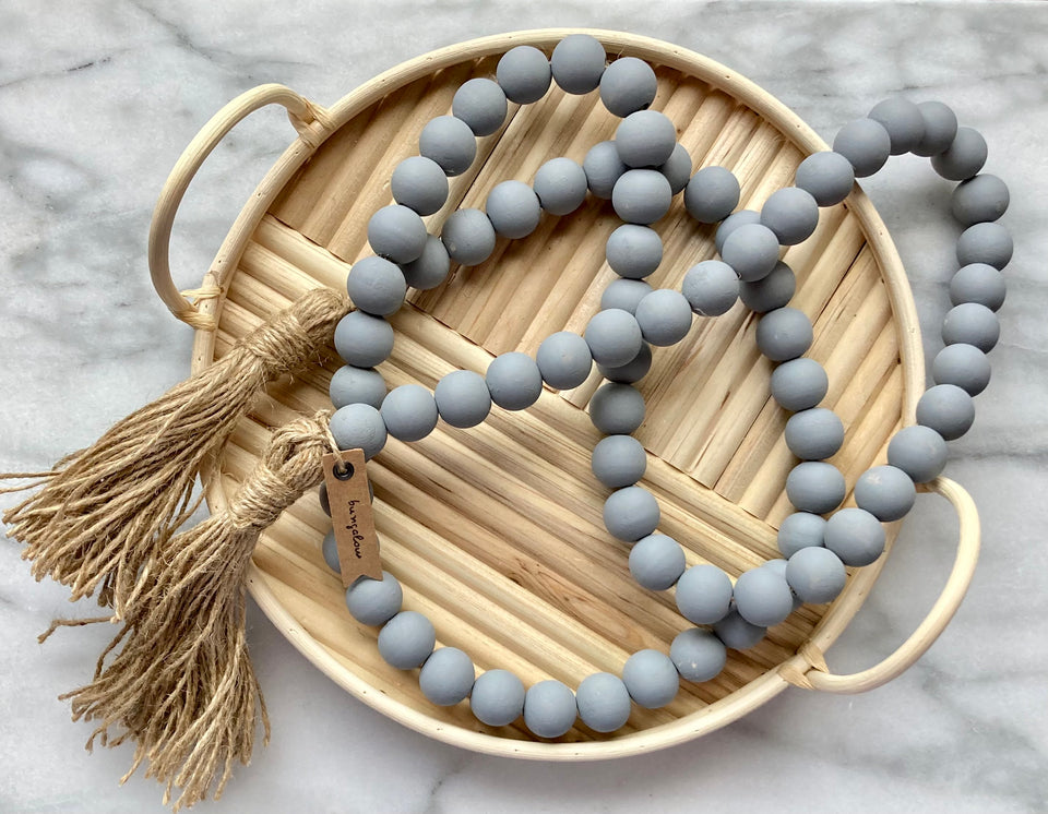 Gray Mango Wood Contentment Beads with jute tassel placed in wooden basket