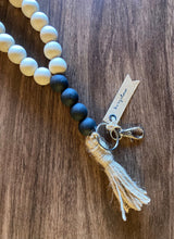Load image into Gallery viewer, Close up of wood bead lanyard with natural beige colored beads and black matte accent beads
