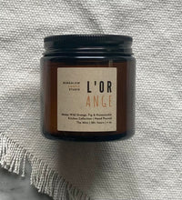 Load image into Gallery viewer, The L&#39;Orange candle scent from the Kitchen Collection, shown in mini 4 oz sized amber-colored glass jar.
