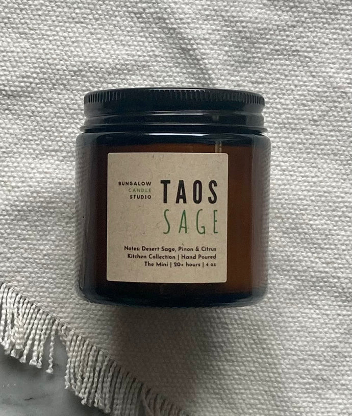 The Taos Sage candle scent from the Kitchen Collection, shown in mini 4 oz sized amber-colored glass jar.
