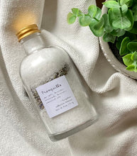 Load image into Gallery viewer, Apothecary jar with bath salts and dried botanicals on a textured white cloth
