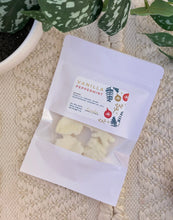 Load image into Gallery viewer, A white pouch of soy wax melts in the Vanilla Peppermint scent laying flat on a woven mat.
