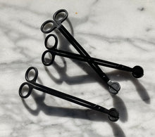 Load image into Gallery viewer, Three matte black metal wick trimmers with round handles lying on a marble surface.
